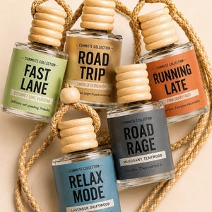 May include: Five glass car air fresheners with wooden tops and braided cords. Each bottle has a different label with phrases like "Fast Lane" and "Road Trip". The scents include Coconut Lime Verbena and Smoked Bergamot.