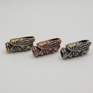 May include: Three metal cicada beads in gold, copper, and silver tones. Each bead features detailed insect body and wing designs. These decorative beads are suitable for jewelry making or other craft projects.