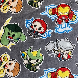 May include: A gray fabric with a repeating pattern of cartoon superheroes. The superheroes include Iron Man, Hulk, Thor, Loki, Captain America, and Black Widow. The fabric is perfect for crafting projects like tote bags, pillows, and quilts.