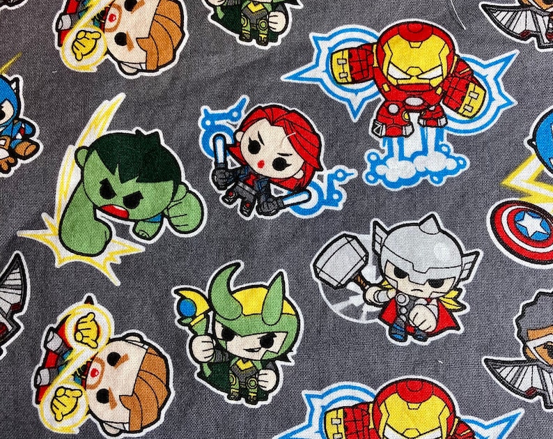 May include: A gray fabric with a repeating pattern of cartoon superheroes. The superheroes include Iron Man, Hulk, Thor, Loki, Captain America, and Black Widow. The fabric is perfect for crafting projects like tote bags, pillows, and quilts.