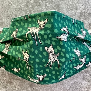 May include: Green fabric face mask with a white repeating pattern of Bambi deer.