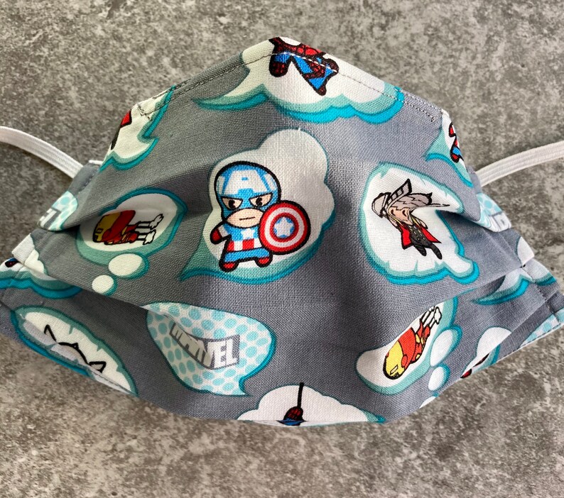 May include: Gray fabric face mask with a repeating pattern of comic book speech bubbles featuring various Marvel superheroes, including Captain America, Iron Man, and Thor. The speech bubbles are in blue and white.