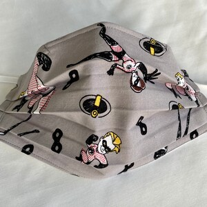 May include: Gray fabric face mask with a repeating pattern of cartoon characters from the Incredibles movie. The characters include Mr. Incredible, Elastigirl, Violet, and Dash.
