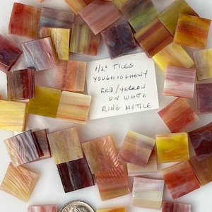 May include: A collection of small, square tiles in shades of red, yellow, and white. The tiles are approximately 1/2 inch in size and have a marbled appearance. Text on a small piece of paper reads "1/2" TILES YOUGH CO GHENY RED/YELLOW ON WHITE RING MOTILE."