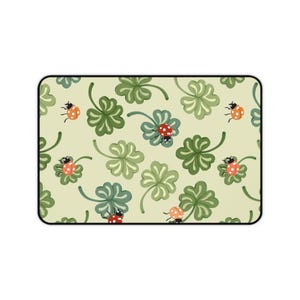 May include: A green and white patterned fabric with red and black ladybugs. The fabric has a repeating pattern of four-leaf clovers and ladybugs.