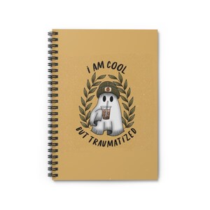 Puede incluir: Una libreta amarilla de espiral con un fantasma de dibujos animados que lleva un sombrero verde y sostiene un té de boba. El texto en la libreta dice "Soy cool pero traumatizado".