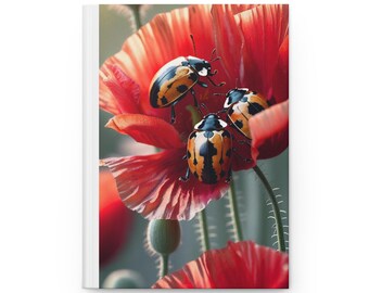 May include: A hardcover journal featuring a vibrant image of three ladybugs on a red poppy flower. The ladybugs have black and orange patterned shells. The journal has a white spine and a soft-focus background.