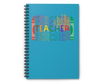 May include: A spiral-bound notebook with a teal cover. The cover features the word "TEACHER" in a repeating pattern with colorful crayon-style lettering. The notebook is designed for teachers and educators.