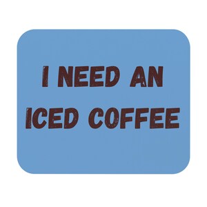 Peut inclure: Un dessous de verre carré bleu clair aux coins arrondis. Le texte "I NEED AN ICED COFFEE" est imprimé en marron foncé, avec une police vieillie, au centre. Le dessous de verre est probablement en matériau absorbant.