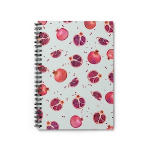 May include: A spiral bound notebook with a light blue cover featuring a repeating pattern of red pomegranates and pomegranate seeds.