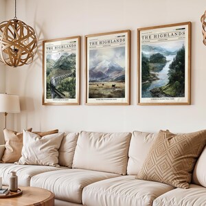 May include: Three framed landscape prints titled "The Highlands" hang above a beige sofa. The prints feature scenic views of mountains, a bridge, and a river. The frames are a light brown colour, and the prints have a vintage newspaper aesthetic.