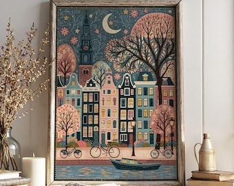 May include: A framed wall art print depicting a nighttime canal scene with narrow Dutch-style houses in shades of pink, blue, and cream. The illustration features a crescent moon, a tall church tower, stylized trees, bicycles, and a small boat.