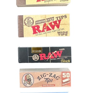 May include: An assortment of rolling tips in various branded boxes. The brands include RAW, Zig-Zag, and Elements. The RAW boxes are brown, black, and tan with red lettering. The Elements box is blue with a colorful gradient.