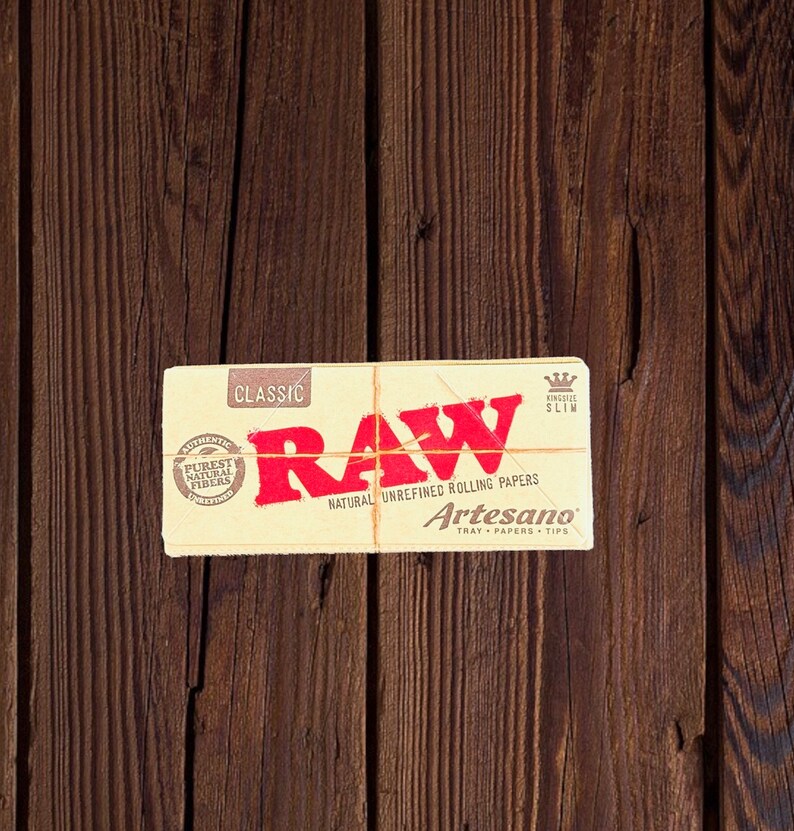 Peut inclure: Un paquet de feuilles &agrave; rouler RAW Classic King Size Slim avec le texte "RAW Natural Unrefined Rolling Papers Artesano Tray Papers Tips" imprim&eacute; sur le devant.