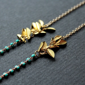 May include: Two gold leaf necklaces with turquoise beads. The necklaces are delicate and feminine.