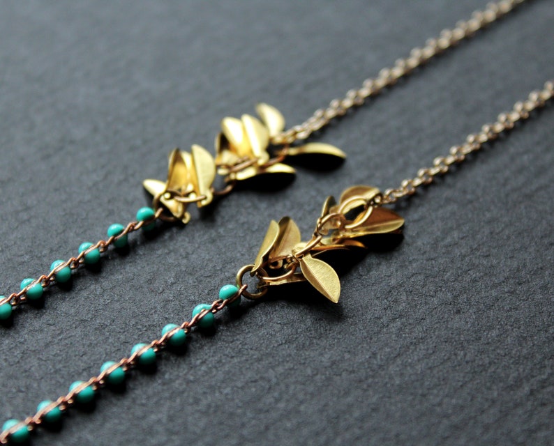 May include: Two gold leaf necklaces with turquoise beads. The necklaces are delicate and feminine.