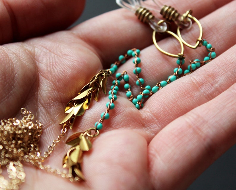 May include: Gold and turquoise beaded earrings with leaf-shaped charms hanging from the bottom.