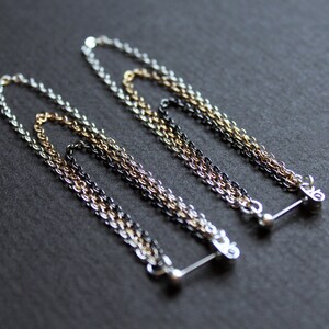 May include: Two silver, gold, and black chain earrings with a bar closure.
