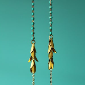 May include: A pair of gold earrings with turquoise beads and a dangling chain of gold leaves.