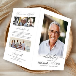 May include: A folded funeral program featuring a large portrait of a smiling man, the text "Celebrating the life of Michael Hodder," dates, and "Forever in our Hearts." The interior includes multiple photographs, an acknowledgement, and service details.