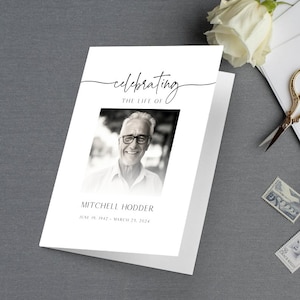 May include: A black and white photo of a man with glasses smiling. The text "celebrating the life of" is above the photo and "Mitchell Hodder June 19, 1942 - March 21, 2024" is below the photo.