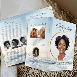 May include: A blue and gold tri-fold funeral program with a photo of a woman on the front cover. The program includes an obituary, order of service, and arrangement details. The text reads "Celebrating the life of Abena Hodder, June 19, 1962 - Aug 27, 2024".