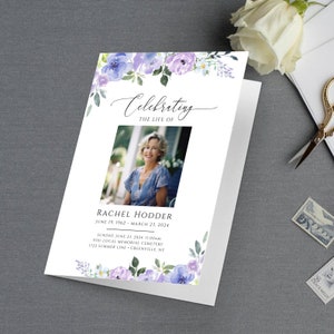 May include: A white memorial card with a watercolour floral border in shades of purple and blue. The card features a photo of a woman, the text "Celebrating the Life of" and the name "Rachel Hodder". The dates "June 19, 1962 - March 23, 2024" are printed below the name. The card also includes details for a memorial service.