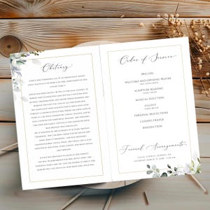 May include: A folded funeral program featuring an obituary on the left and an order of service on the right. The document has a white background with gold borders and watercolor eucalyptus leaf illustrations in the corners, printed in black text.