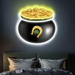 Könnte beinhalten: Ein Neonschild, das einen schwarzen Topf voller Goldmünzen, ein goldenes Hufeisen und ein grünes Kleeblatt zeigt. Das Schild befindet sich an einer dunklen Wand über einem Bett mit grauer Bettwäsche. Das Schild hat einen weißen Umriss und einen gelben Schein.