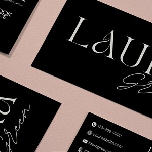 Op de afbeelding: Zwarte visitekaartjes met witte tekst en een QR-code. De kaarten tonen de naam "Laura Green" in een stijlvol lettertype. Contactgegevens staan ook op de kaarten, zoals een telefoonnummer en websiteadres. De achtergrond is lichtroze.