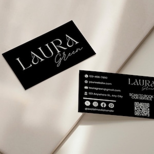 Op de afbeelding: Twee zwarte visitekaartjes met witte tekst. De kaarten tonen de naam "LAURA Green" in elegant schrift. E&eacute;n kaart bevat contactgegevens: telefoonnummer, website, e-mail en social media handles. Er is ook een QR-code aanwezig.