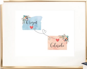 May include: A framed print with a watercolor illustration of the states of Oregon and Colorado. The states are connected by a line with hearts. The text "Oregon" and "Colorado" is written in cursive.