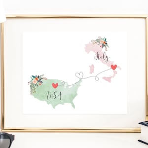 Könnte beinhalten: Ein Aquarelldruck einer Karte der USA und Italiens, die durch eine gepunktete Linie mit Herzen verbunden sind. Die USA sind grün und der Text "USA" ist auf der Karte geschrieben. Italien ist rosa und der Text "Italien" ist auf der Karte geschrieben.