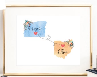 May include: A watercolor print of the states of Oregon and Ohio with a red heart connecting them. The states are labeled with the text "Oregon" and "Ohio".