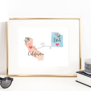 Puede incluir: Una impresión enmarcada con una ilustración de acuarela de los estados de Utah y California conectados por una línea con corazones. El texto "Utah" y "California" está escrito debajo de cada estado.