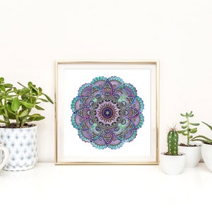 May include: A framed print of a colorful mandala with blue, purple, and green hues. The mandala is surrounded by a gold frame and is displayed on a white shelf with potted plants.