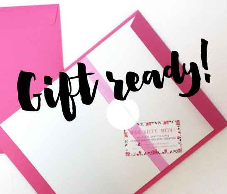 May include: A pink envelope with a white envelope inside. The white envelope has a pink stripe across it and the text "Gift ready!" in black. The white envelope also has a small business card with the text "Mad Kitty Media" on it.
