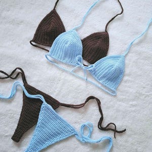 May include: A crocheted bikini set with a blue and brown top and matching bottom. The top is a triangle style with adjustable straps and ties at the front. The bottom is a cheeky style with ties on the sides.