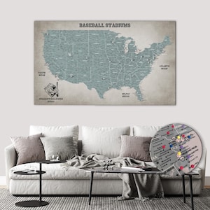 May include: A wall map of the United States titled BASEBALL STADIUMS, featuring a muted blue-grey landmass on a beige background. The map includes state borders, city names, and a baseball player illustration. A circular inset shows a detailed view of New Jersey with colourful push pins marking specific stadium locations.
