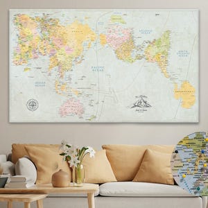 May include: A large world map print with a vintage aesthetic, showing detailed geographical information and country names. The map is mounted on a wall above a sofa. A smaller, circular map with pins is visible.