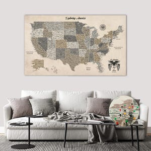 Op de afbeelding: Een grote rechthoekige wandkaart getiteld Exploring America, met de Verenigde Staten in tinten beige, grijs en bruin. Het bevat een kompasroos, labels voor oceanen en een ronde inzetkaart van Pennsylvania met kleurrijke punaises.