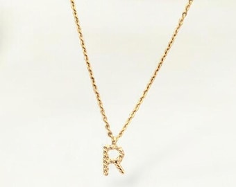 May include: A gold chain necklace with a small, diamond-encrusted letter 'R' pendant.