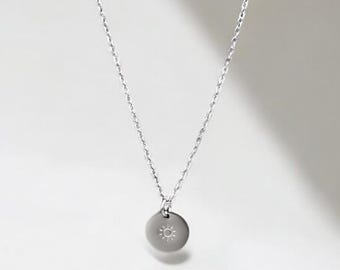 May include: A silver chain necklace with a small round pendant featuring a single diamond in the center.
