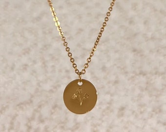May include: A gold chain necklace with a round pendant featuring a delicate floral design.