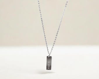 May include: A silver chain necklace with a rectangular pendant that says "peace" in all lowercase letters.