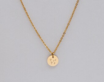 May include: A gold chain necklace with a small round pendant featuring a design of five stars.