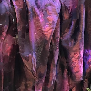 May include: Purple fabric with a floral pattern. The fabric has a soft, silky texture and is perfect for creating garments or home decor.
