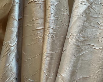 Polyester fabric; pleated surface with sheen in a pale shade of silver.