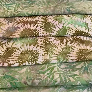 May include: A stack of green and brown fabric with a floral pattern. The fabric is folded in a way that shows the different patterns.