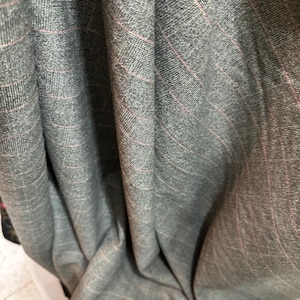 May include: Gray fabric with thin pink stripes. The fabric is folded and draped.